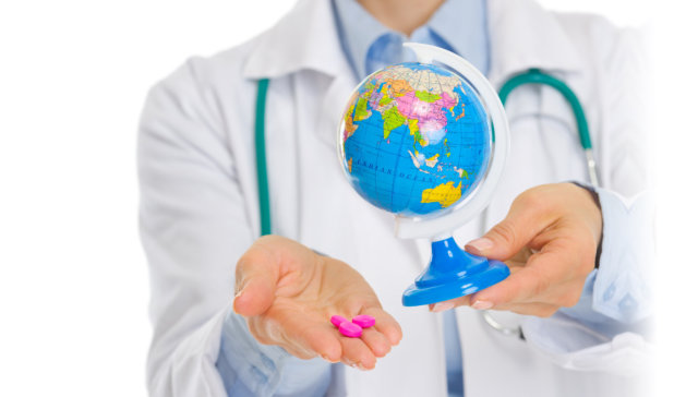 hand holding a globe and medicine tablets